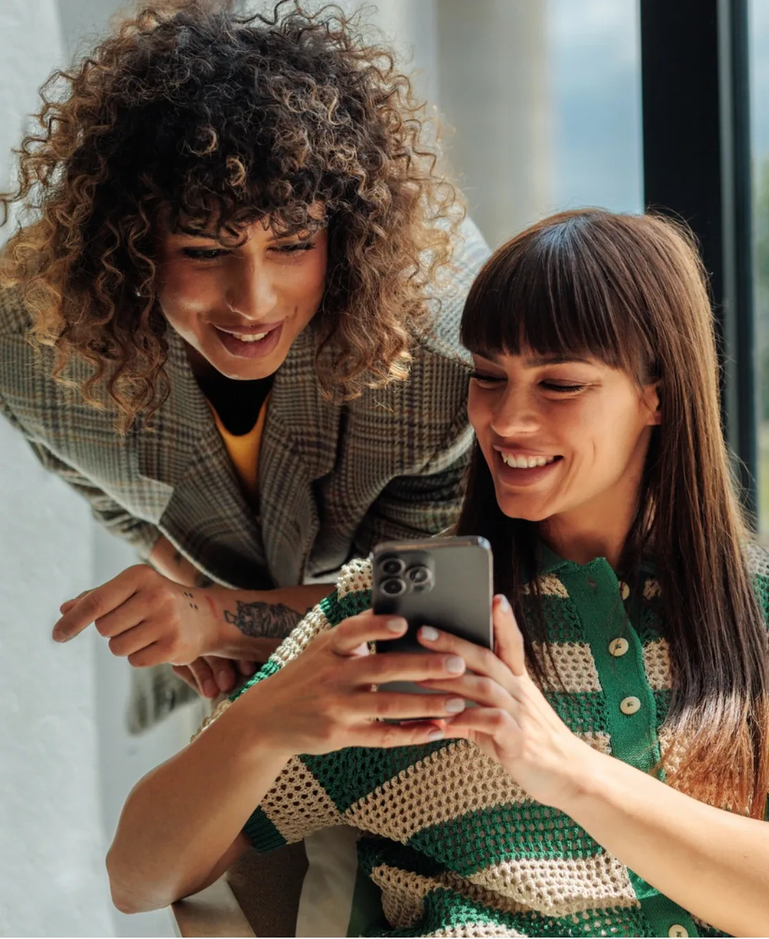Two women laughing while looking at a phone together
