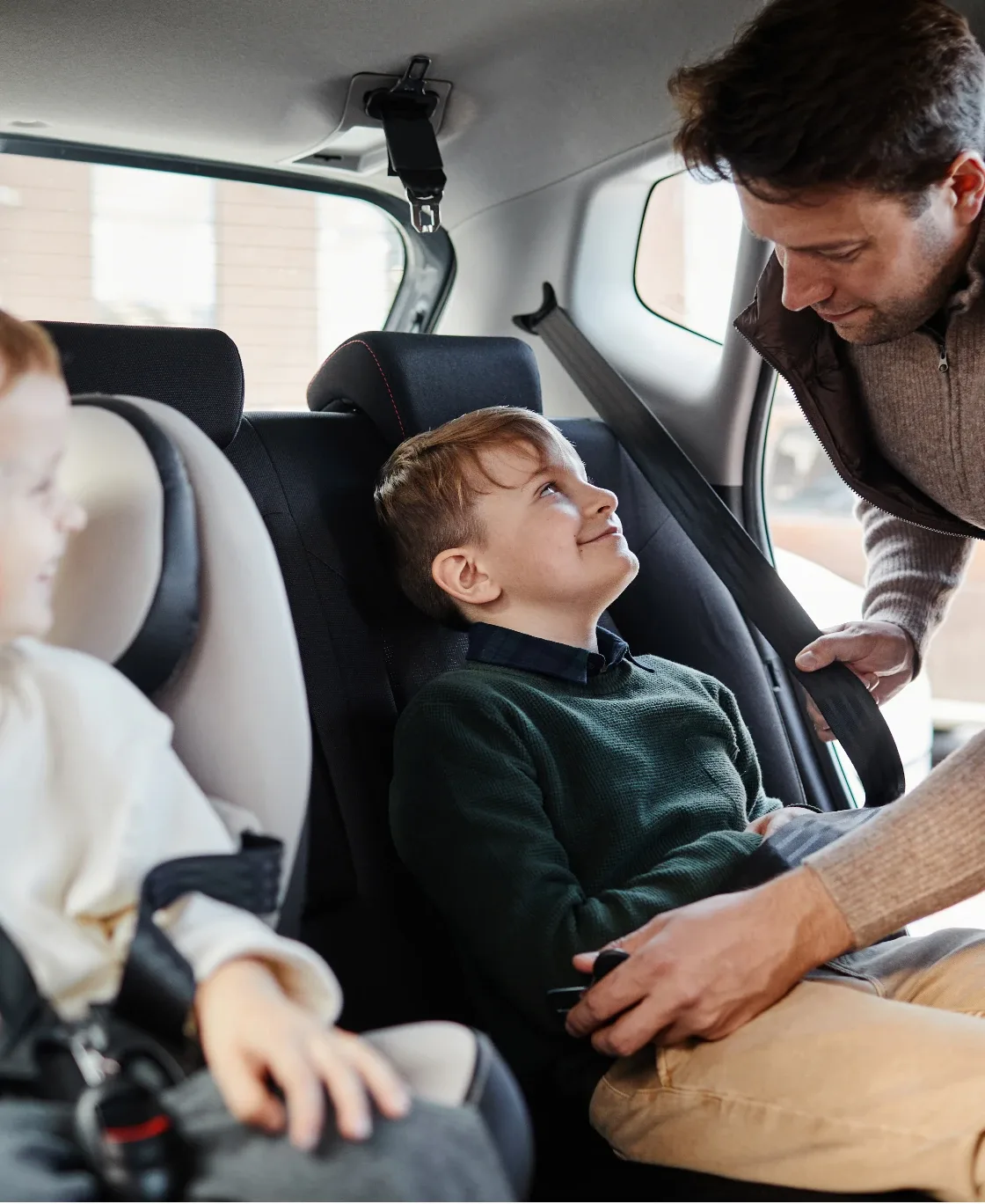 Father buckling his children into car seats