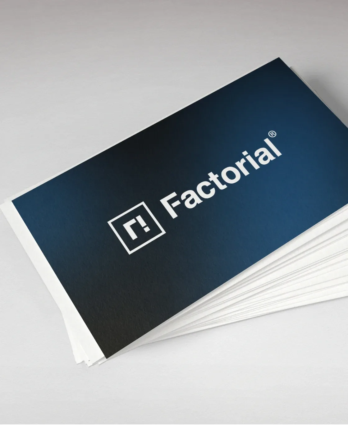 Stack of Factorial business cards with the logo on dark blue