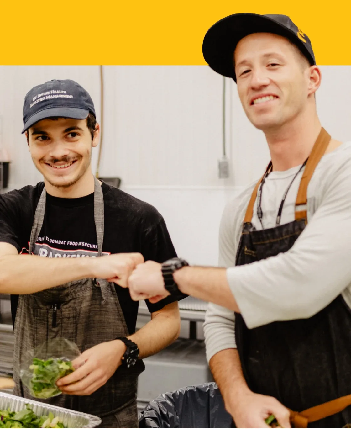 Two smiling kitchen workers bumping fists