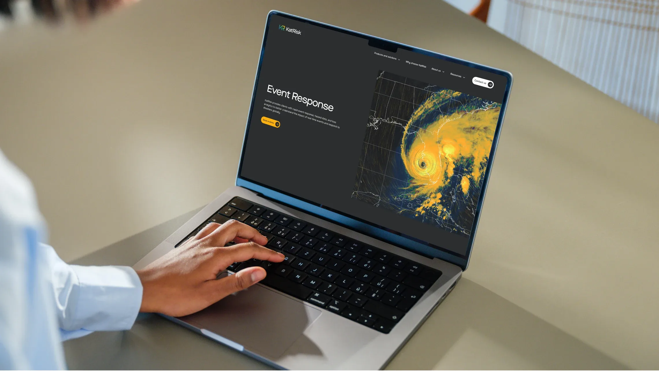 Person using the KatRisk event response page with a hurricane map on a laptop