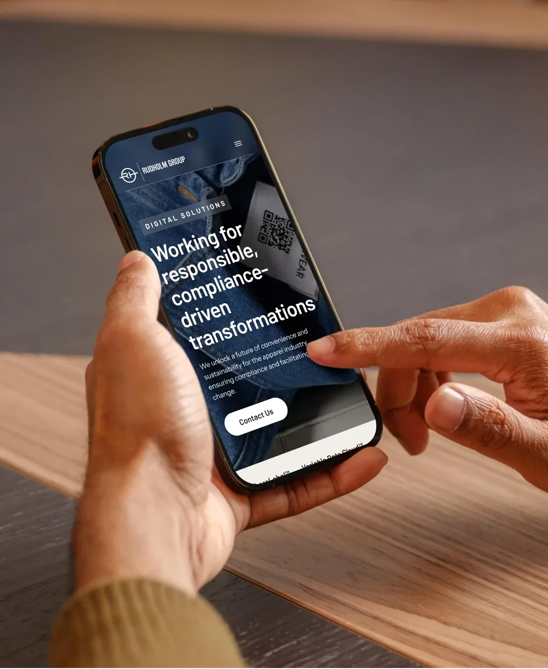 Hands holding a phone with the Rudholm page on compliance-driven transformations