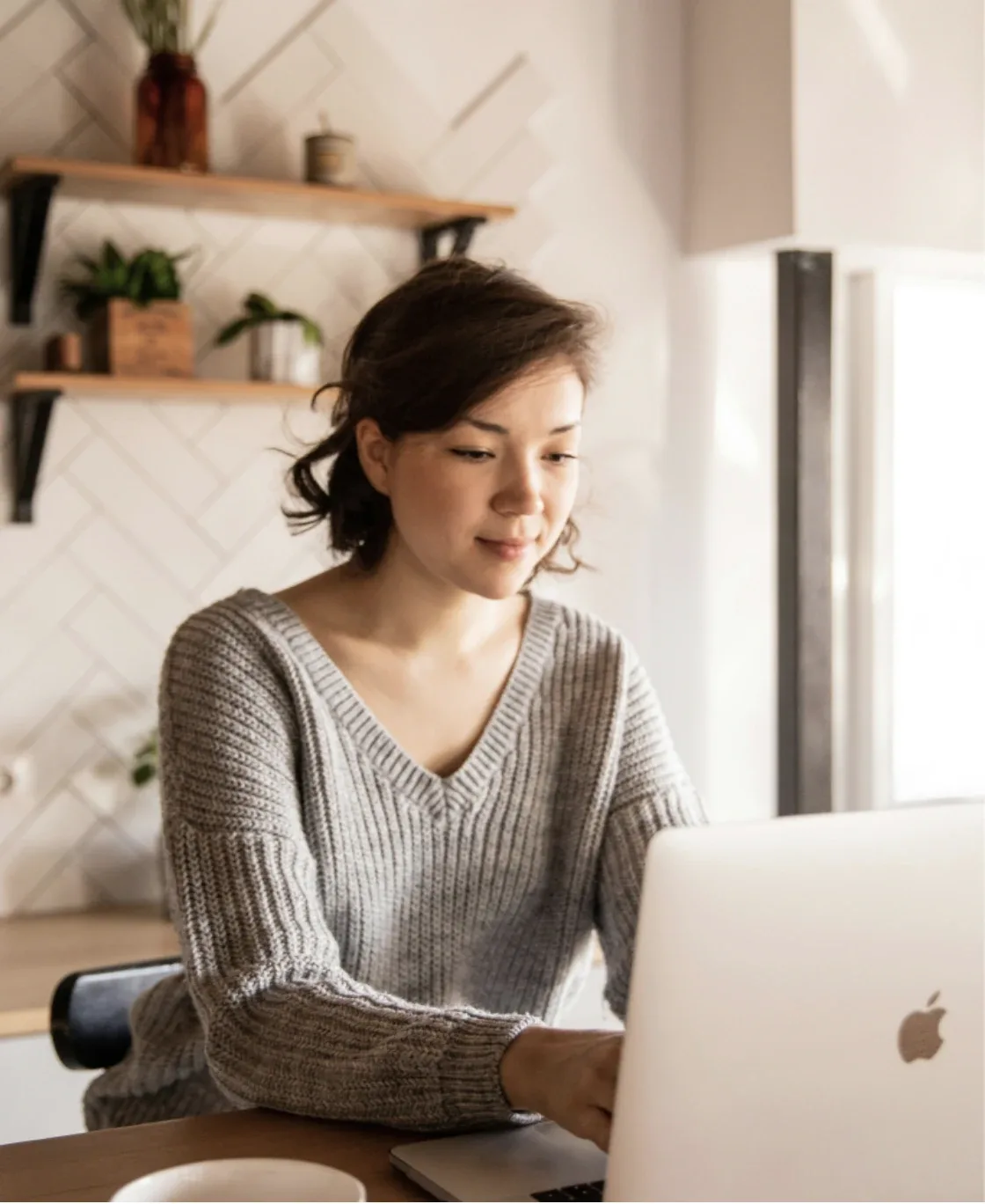 Smiling woman working on a laptop in a kitchen