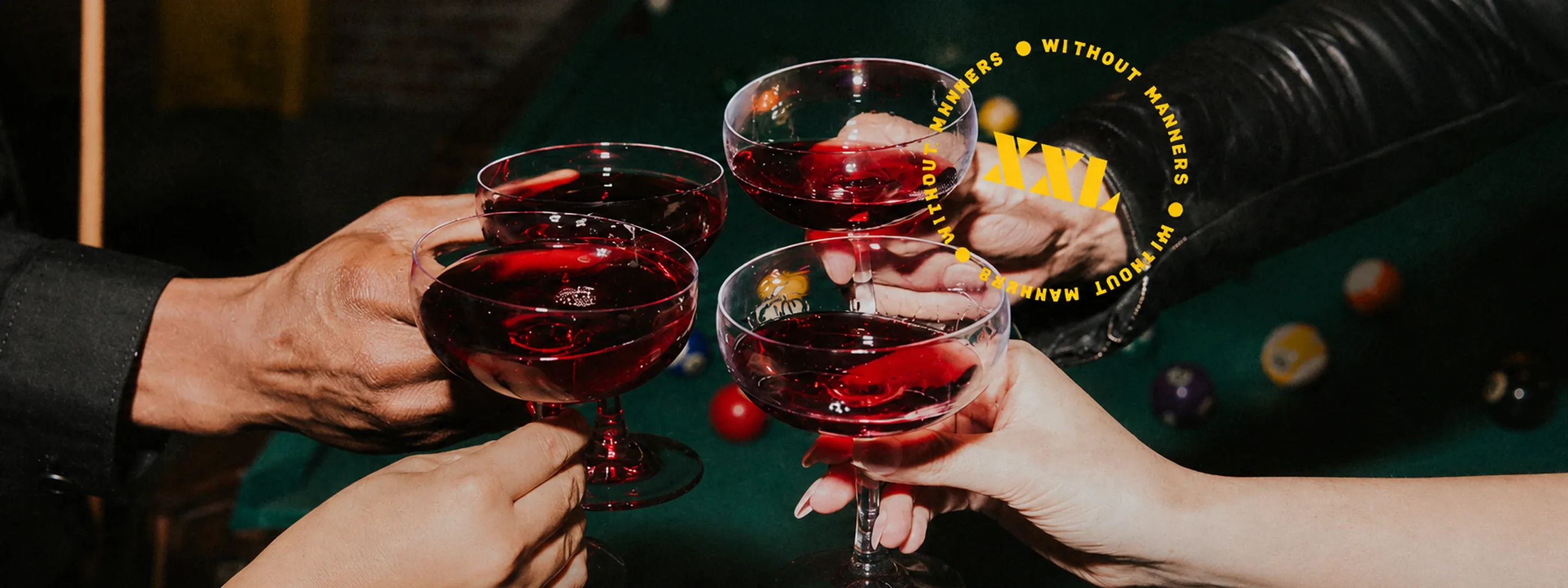 Friends toasting with glasses of red XXL wine over a pool table
