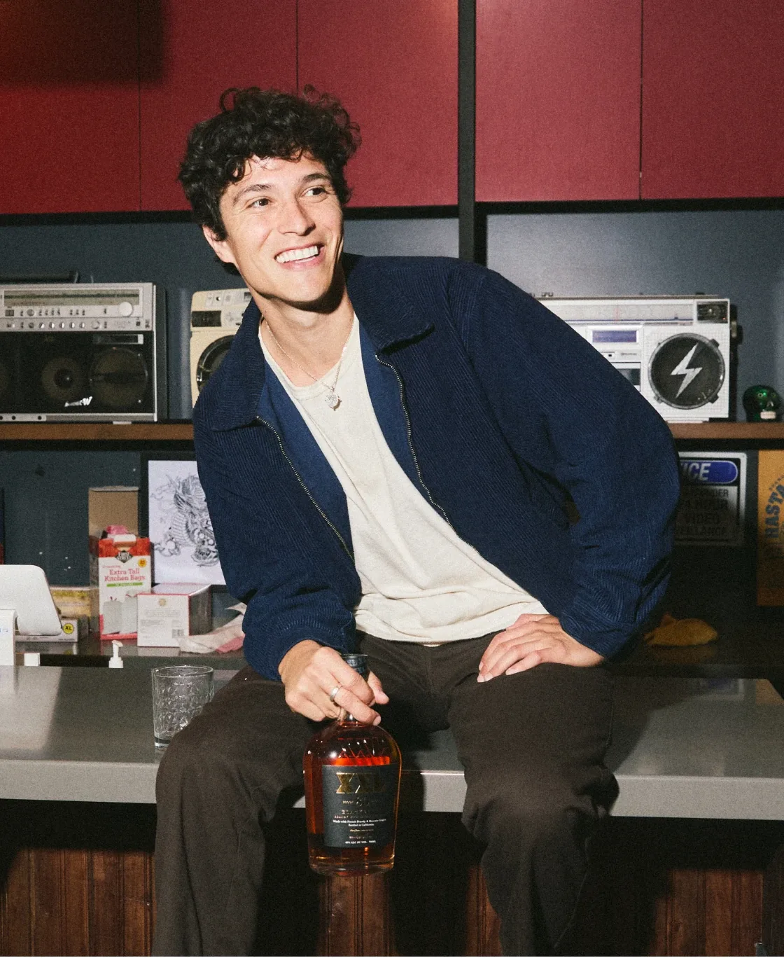 Smiling man sitting in a studio with a bottle of XXL