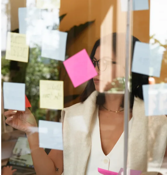 A designer arranging sticky notes on a glass wall during a workshop