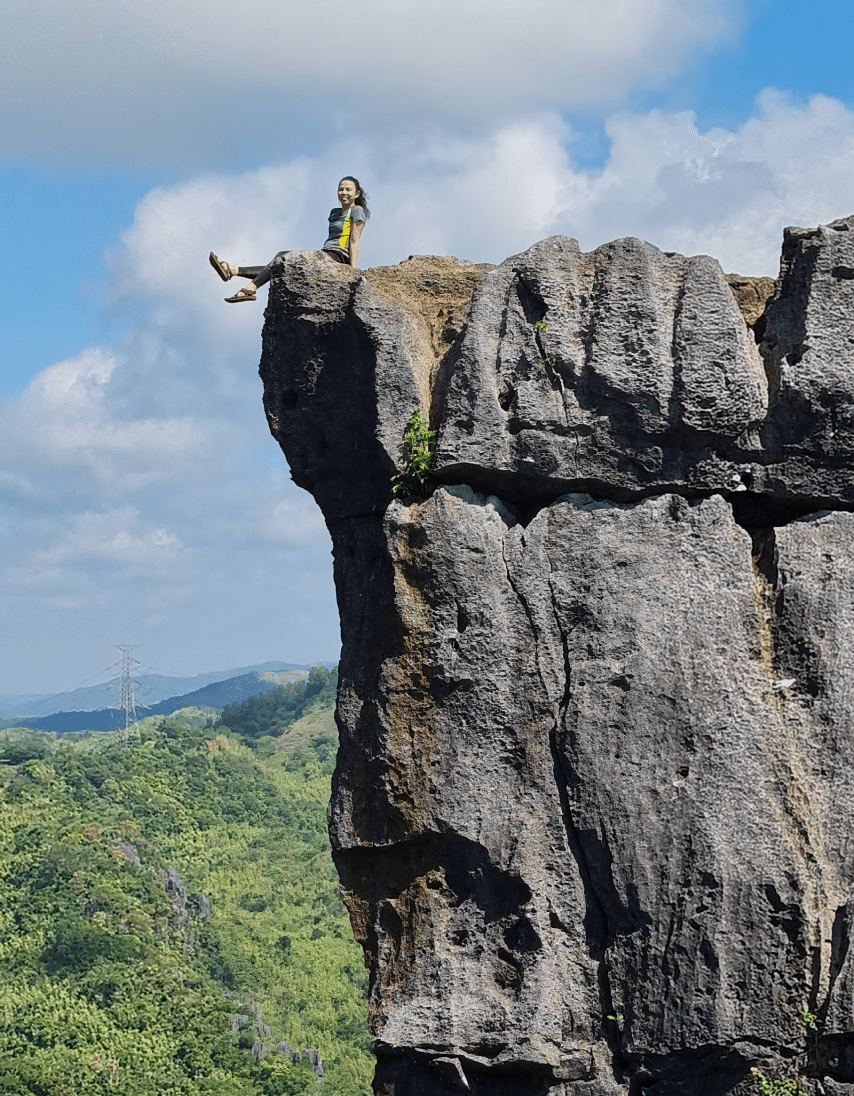 A photo of a woman siting on top of a huge rock